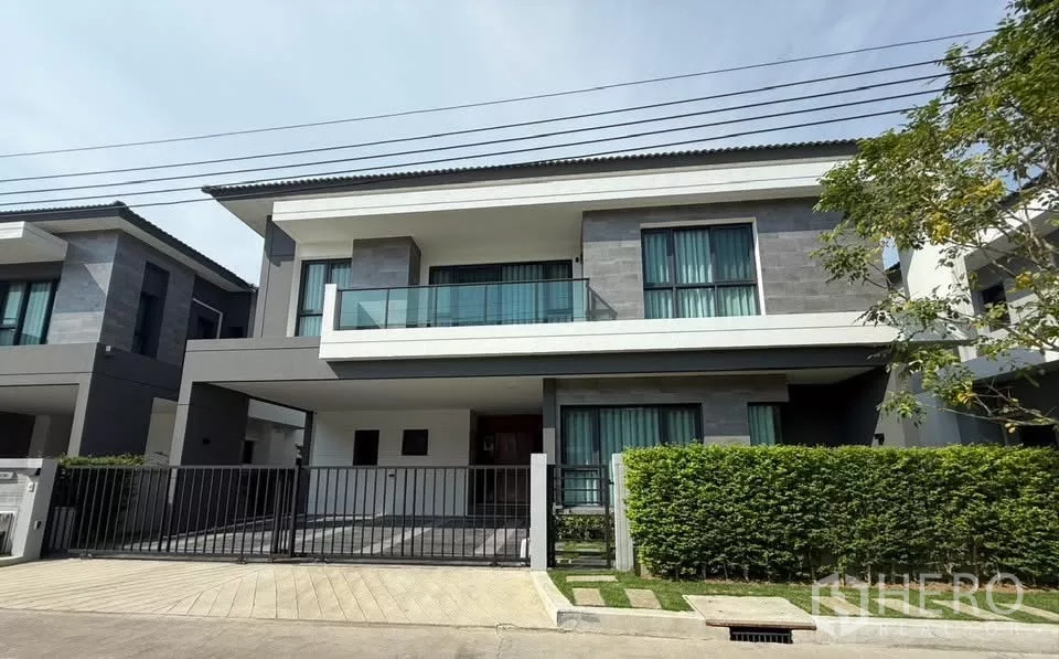 独立式住宅 出租在Bang Phli, Samut Prakan - The City Bangna 现代两层独栋别墅，带围栏车道与修剪整齐的绿篱。