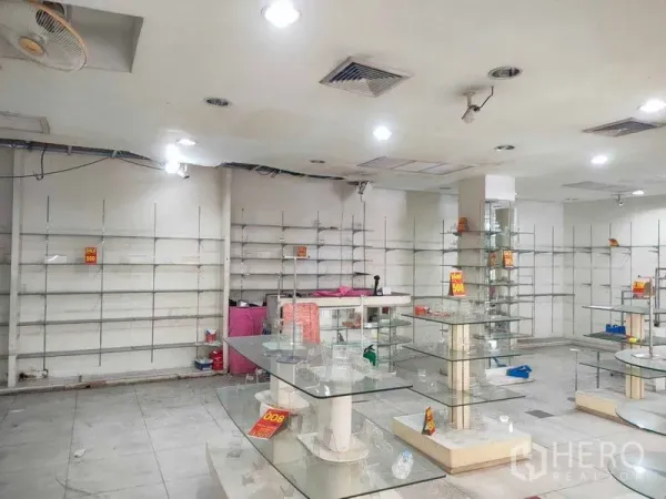 Shophouse for rent in Watthana, Bangkok - Spacious shop interior with ceiling lights, wall shelving and glass counters ready for merchandising.