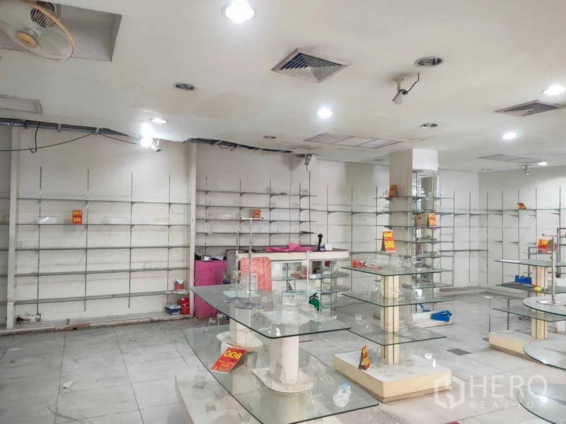 Shophouse for rent in Watthana, Bangkok - Spacious shop interior with ceiling lights, wall shelving and glass counters ready for merchandising.