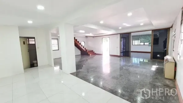独立式住宅 出租在Lat Phrao, Bangkok - 明亮的开放式客厅，嵌灯照明，拼接地砖与木楼梯。