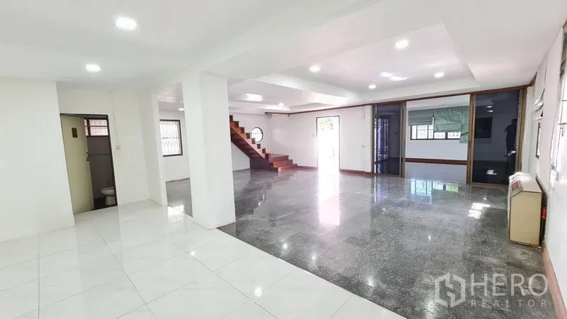 独立式住宅 出租在Lat Phrao, Bangkok - 明亮的开放式客厅，嵌灯照明，拼接地砖与木楼梯。