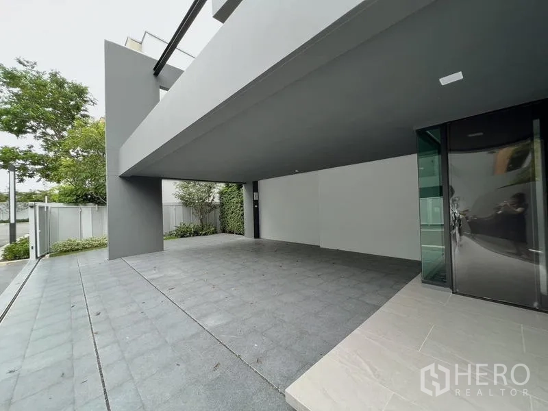 Detached House for rent or sale in Saphan Sung, Bangkok - Covered parking bay beneath the house with gate and landscaping.