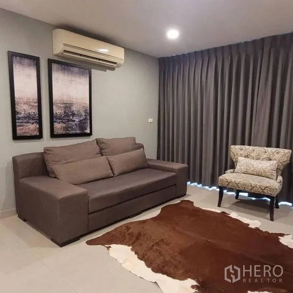公寓 出租在Watthana, Bangkok - 舒适的休息角，灰色沙发、单人椅和遮光窗帘。