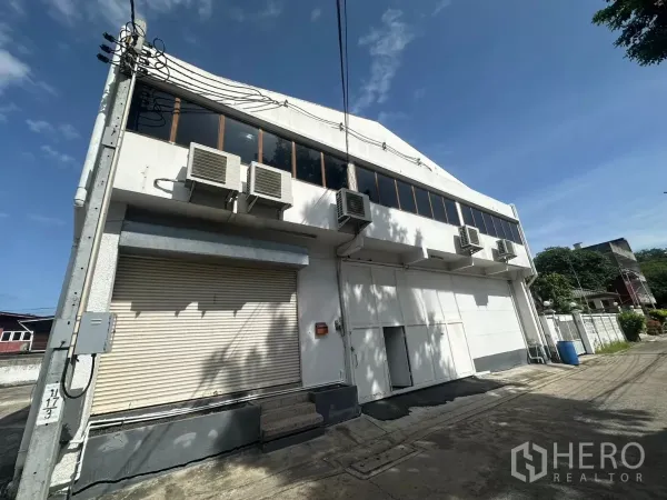 货栈 出租在Bang Na, Bangkok - 临街两层仓库外观，卷闸门与多台空调机组，位于邦那。