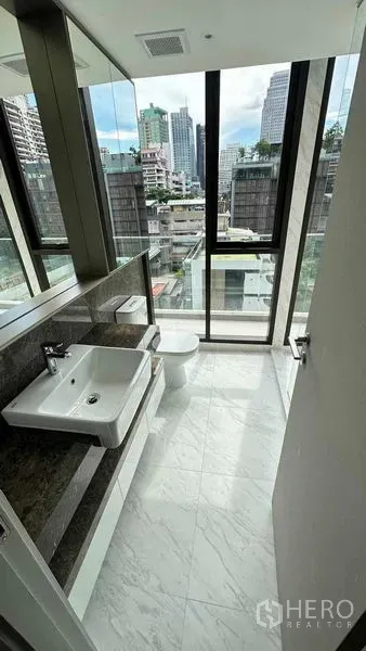 คอนโด ให้เช่าในWatthana, Bangkok - ห้องน้ำปูหินอ่อนพร้อมอ่างล้างหน้าและโถสุขภัณฑ์ มีกระจกสูงจากพื้นจรดเพดานมองเห็นวิวเมือง