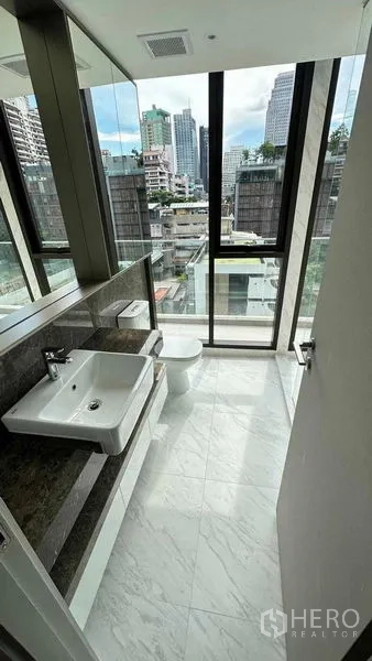 คอนโด ให้เช่าในWatthana, Bangkok - ห้องน้ำปูหินอ่อนพร้อมอ่างล้างหน้าและโถสุขภัณฑ์ มีกระจกสูงจากพื้นจรดเพดานมองเห็นวิวเมือง