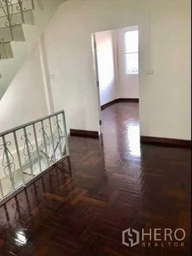 带办公室的家 出租或出售在Watthana, Bangkok - 明亮的楼梯平台，抛光拼花木地板、白墙和通往卧室的门。