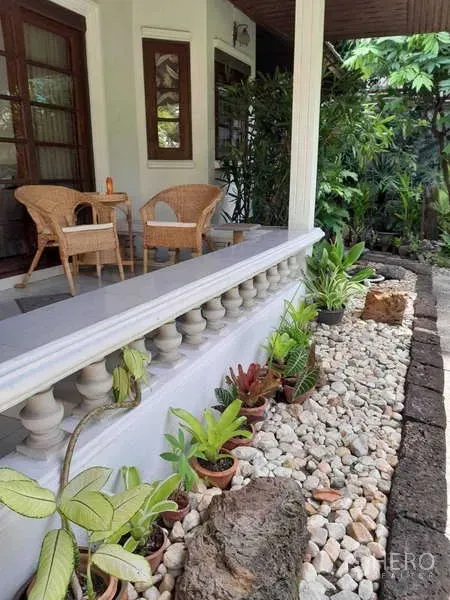 บ้าน ให้เช่าในKhlong Toei, Bangkok - ชานระเบียงมีหลังคาพร้อมเก้าอี้หวาย และแปลงปลูกต้นไม้โรยหินกรวดข้างราวระเบียง