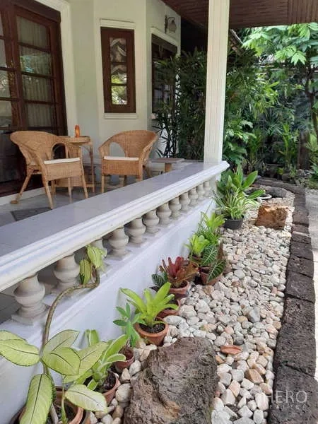 บ้าน ให้เช่าในKhlong Toei, Bangkok - ชานระเบียงมีหลังคาพร้อมเก้าอี้หวาย และแปลงปลูกต้นไม้โรยหินกรวดข้างราวระเบียง