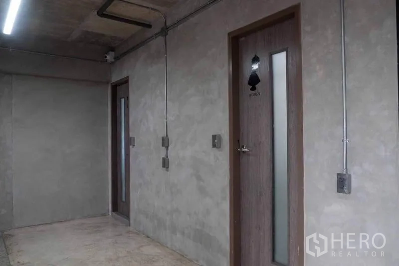Home Office for rent or sale in Lak Si, Bangkok - Concrete corridor with exposed conduits and restroom doors.