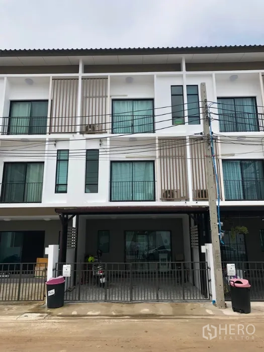 Townhouse for sale in Bang Kapi, Bangkok - Modern three-storey townhouse facade with gated covered carport and large windows.