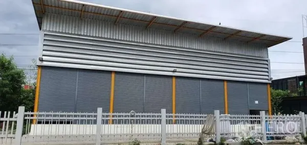 Warehouse for rent in Khlong Toei, Bangkok - Modern warehouse exterior with metal cladding, long roof eaves and gated frontage with parking.