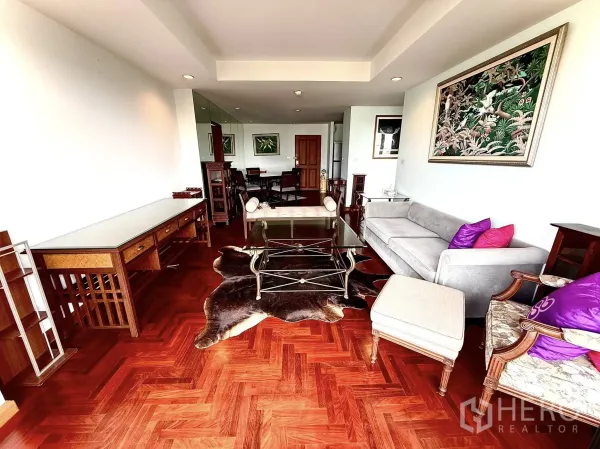 คอนโด ให้เช่าในSathon, Bangkok - ห้องนั่งเล่นกว้างพร้อมโซฟาสีเทา โต๊ะกลางกระจก และพรมหนังวัว.