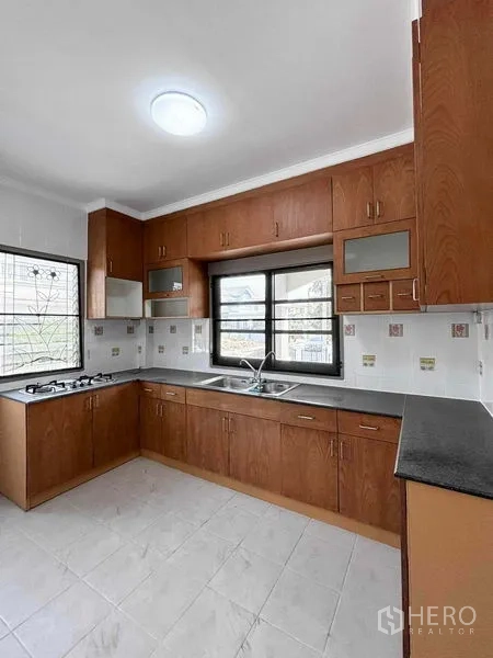Detached House for rent or sale - L-shaped kitchen with wooden cabinets, gas hob, sink and tile backsplash.