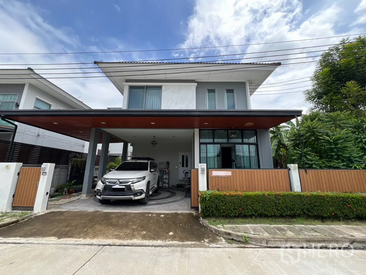 独立式住宅 出租或出售在Lat Krabang, Bangkok - 两层独栋别墅外观，带遮棚车位与前院围栏，位于曼谷叻甲挽区