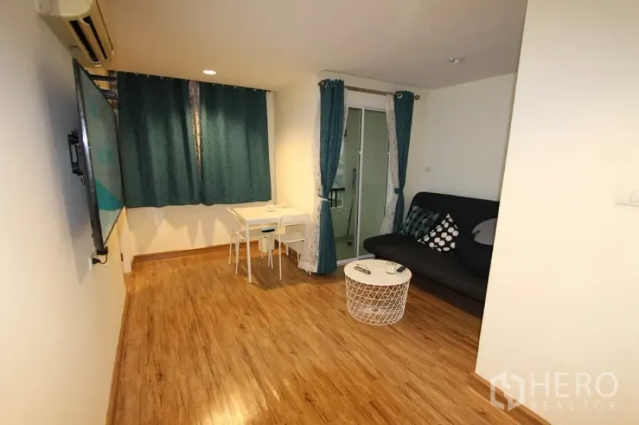 Condominium for rent or sale in Wang Thonglang, Bangkok - Living-dining area with small table, sofa by the balcony, and warm wood-look flooring.