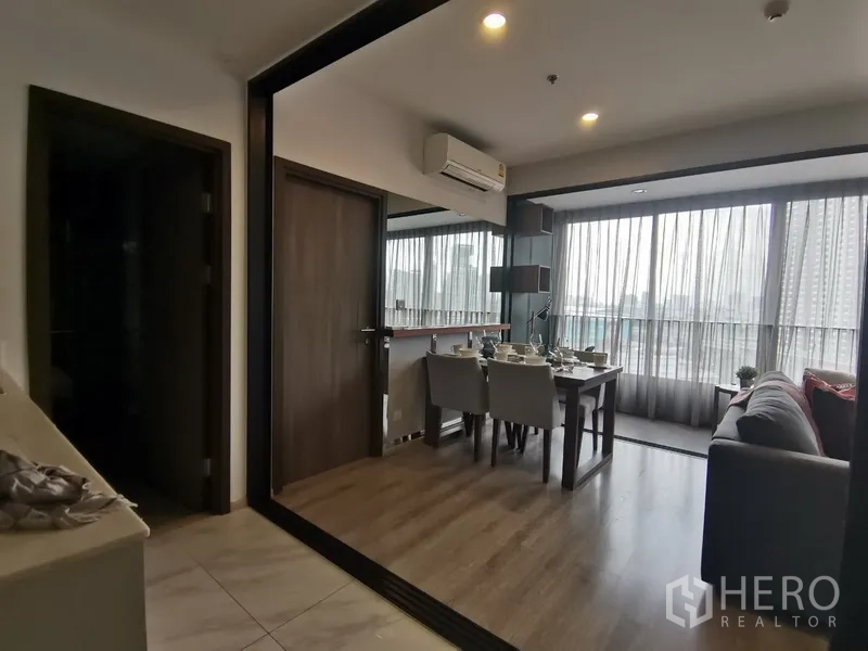 คอนโด ให้เช่าในHuai Khwang, Bangkok - มุมทานอาหารและนั่งเล่นเปิดออกสู่ระเบียงกระจก พร้อมผ้าม่านโปร่งและพื้นลายไม้โทนอุ่น