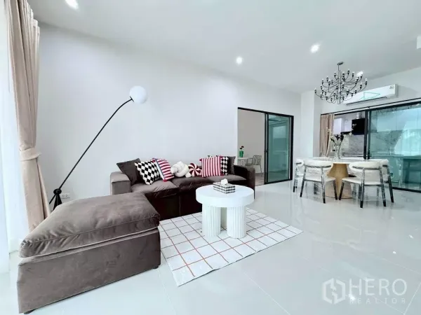 Townhouse for rent in Saphan Sung, Bangkok - Bright open-plan living and dining area with sectional sofa and chandelier.