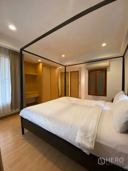 คอนโด ให้เช่าในWatthana, Bangkok - ห้องนอนพร้อมเตียงสี่เสา ตู้เสื้อผ้า และมุมโต๊ะแต่งตัวบิลท์อินโทนไม้