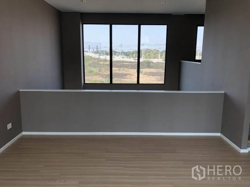 Townhouse for rent or sale in Saphan Sung, Bangkok - Upper-floor open space with wide windows and neighborhood view.