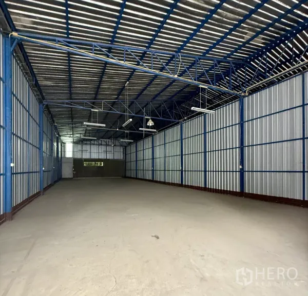 Warehouse for rent in Bueng Kum, Bangkok - Spacious warehouse interior with blue steel trusses, high gabled roof and concrete floor.
