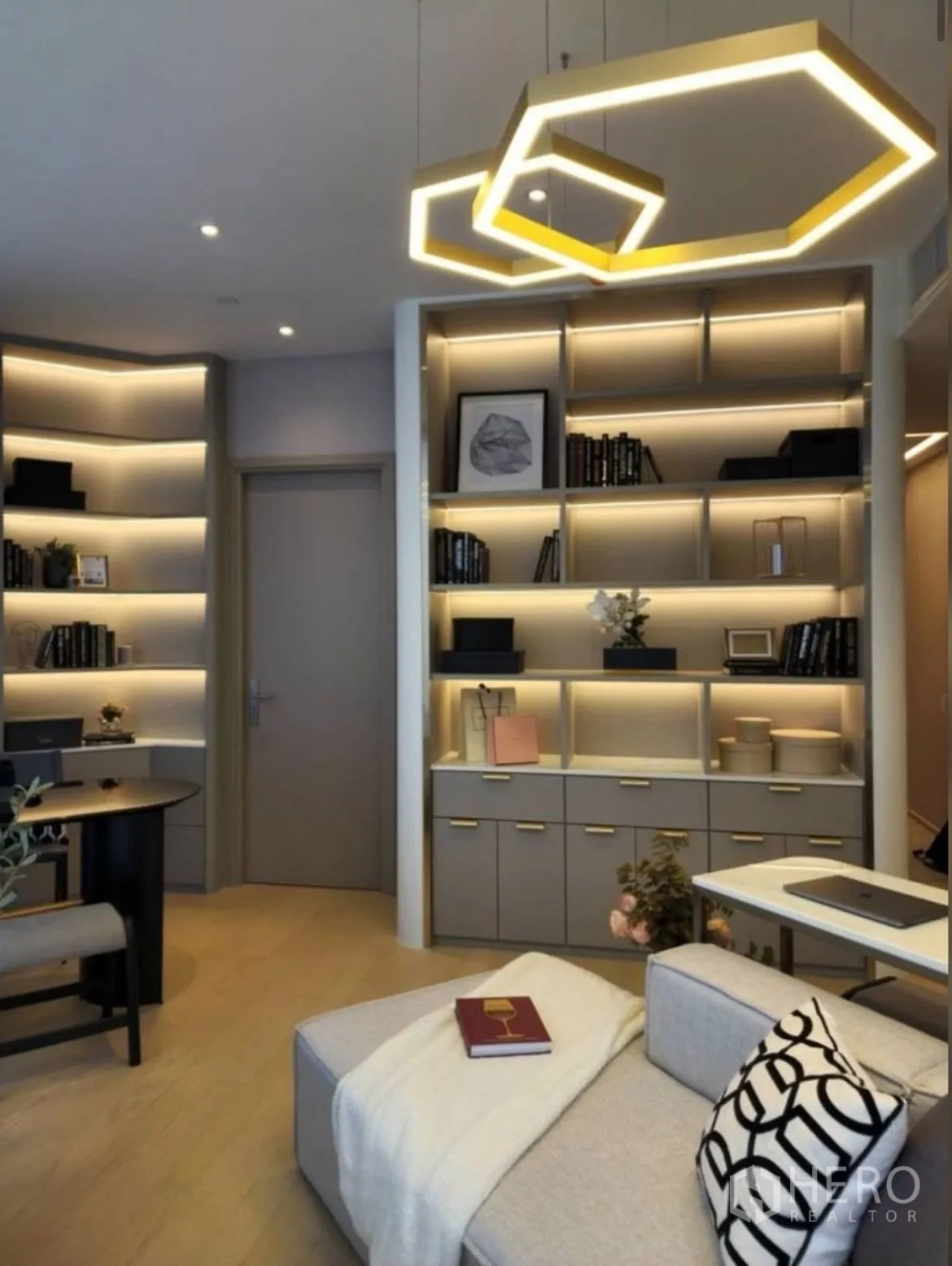 Condominium for rent in Din Daeng, Bangkok - Cozy sofa beneath gold geometric lights with a wall of custom shelving.
