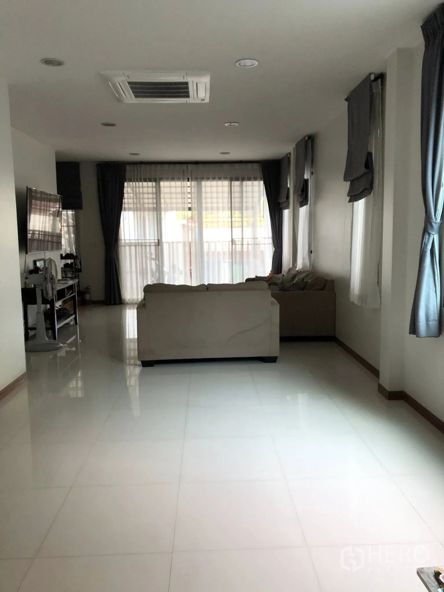 Townhouse for sale in Phra Khanong, Bangkok - Spacious open-plan living room with glossy white tiles, large windows and ceiling cassette air-conditioning.