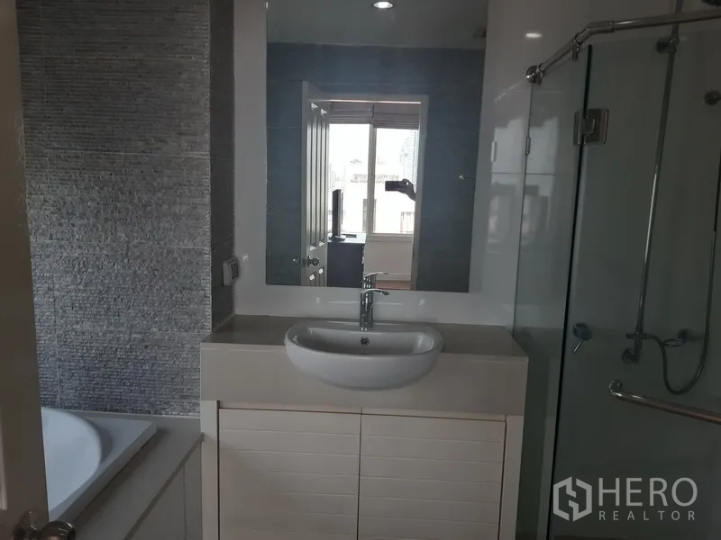 Condominium for rent in Khlong Toei, Bangkok - Primary bathroom featuring a vanity, bathtub, and separate glass shower.
