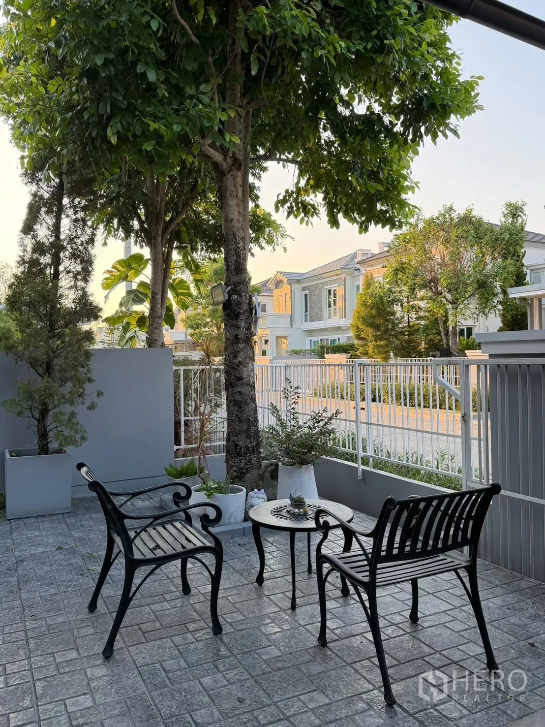 半独立式住宅 for rent in Prawet, Bangkok - 前院露台，树荫下摆放两张金属长椅和一张圆桌