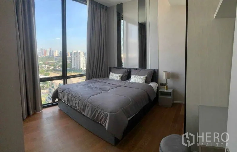 公寓 出租在Pathum Wan, Bangkok - 巴吞旺待租公寓的明亮卧室，巨幅窗户、城市天际线与木地板。