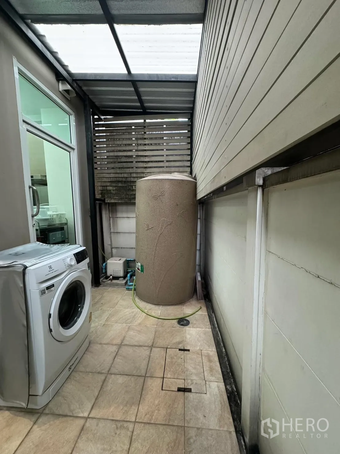 Townhouse for rent in Suan Luang, Bangkok - Covered utility terrace with washing machine and large water tank beside sliding door.