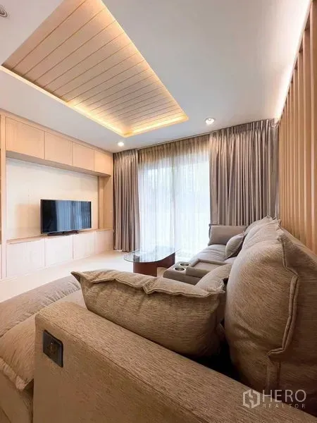 Condominium for rent - Another angle of the living room with sofa, TV and sheer curtains.
