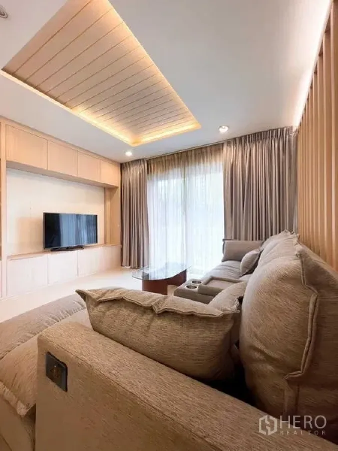 Condominium for rent - Another angle of the living room with sofa, TV and sheer curtains.