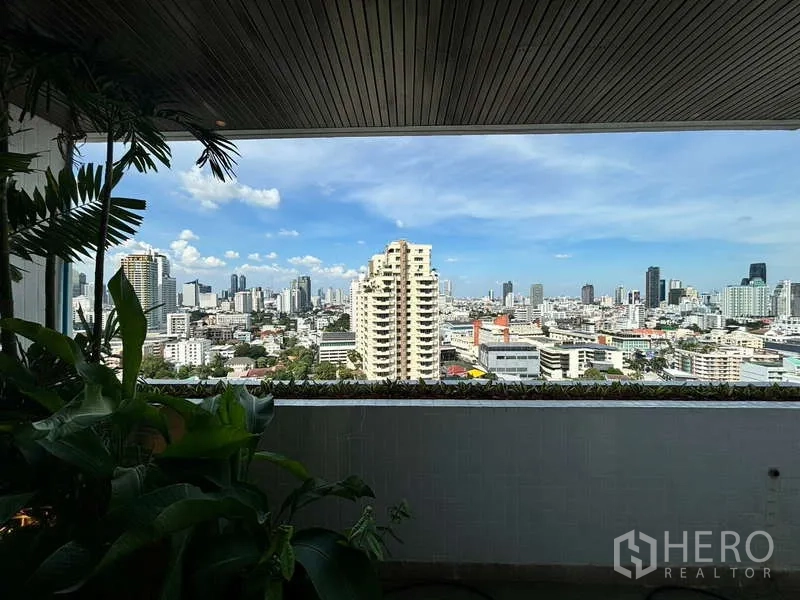 Condominium for rent in Watthana, Bangkok - Covered terrace framed by plants overlooking the city skyline.