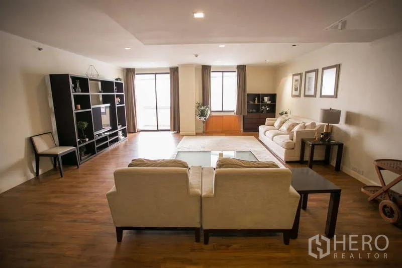 Condominium for rent or sale in Watthana, Bangkok - Vast living room with balcony doors, entertainment shelving and sofas.