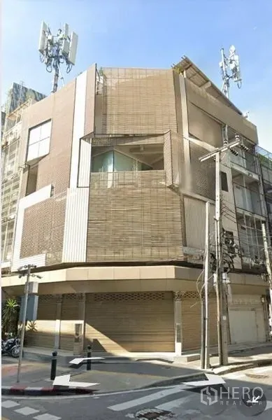 零售空间 出租 - 街景视角的现代转角商业楼，卷闸门关闭。