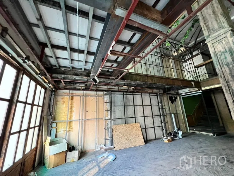 Shophouse for rent in Watthana, Bangkok - Ground-floor space with partial mezzanine, ladder, and staircase in raw condition.