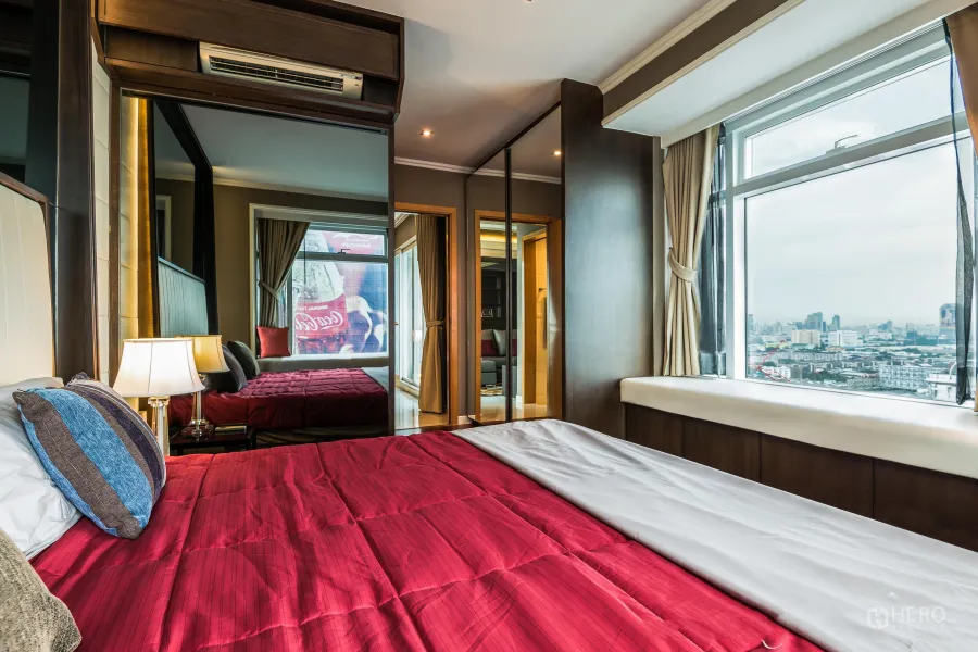 公寓 出租在Ratchathewi, Bangkok - 转角主卧，红色床品，镜面衣柜与大窗，城市景观开阔