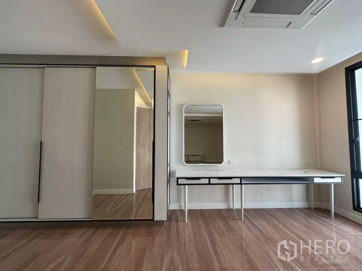 Townhouse for rent in Watthana, Bangkok - Wardrobe wall with sliding doors and a dressing counter under the window.