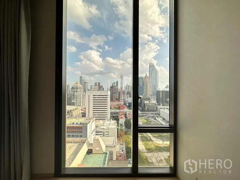 公寓 出租在Pathum Wan, Bangkok - 晴天从公寓窗户望见的高层城市景观。