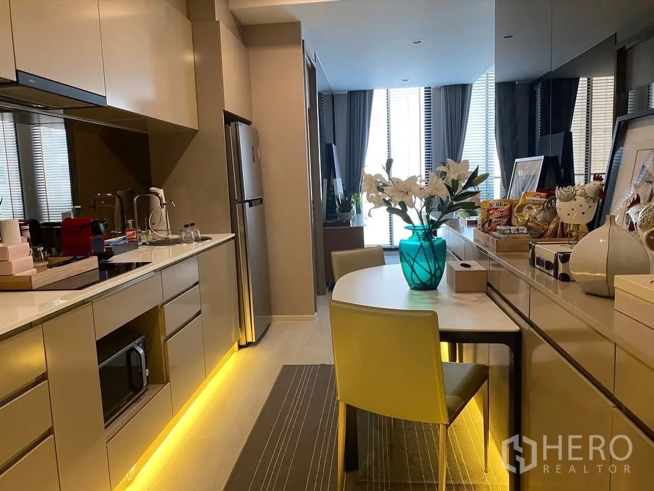 公寓 for rent in Pathum Wan, Bangkok - 长廊式厨房，嵌入式电器、早餐桌与镜面墙体。
