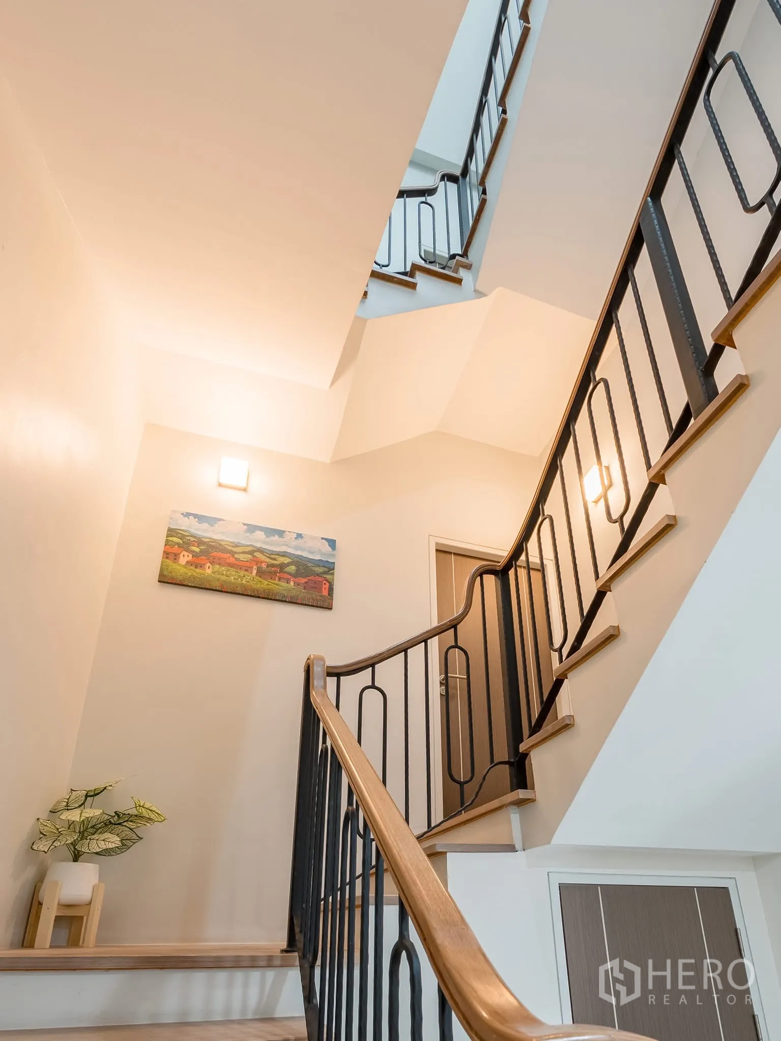Home Office for rent in Khlong Toei, Bangkok - Staircase with black metal railing and wooden handrail, decorated with wall art.