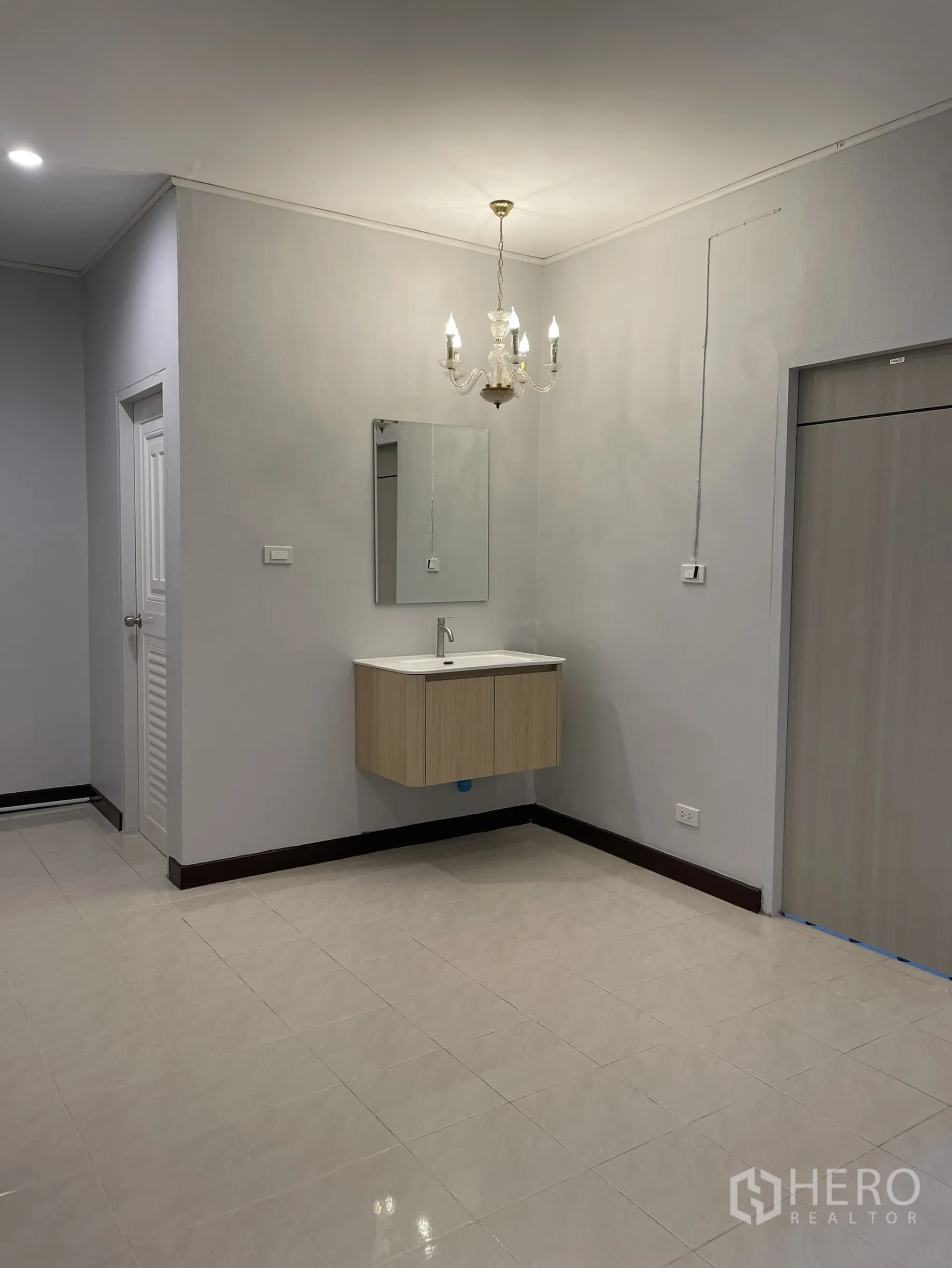 店屋 for rent in Bang Kapi, Bangkok - 近景展示枝形吊灯、悬空洗手台与镜面，空间以中性色瓷砖铺设。