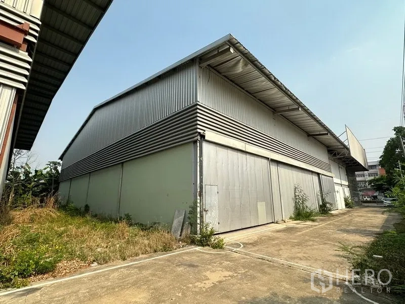 Warehouse for rent in Lam Luk Ka, Pathum Thani - Rear exterior of metal-clad warehouse with oversized sliding doors and loading apron.