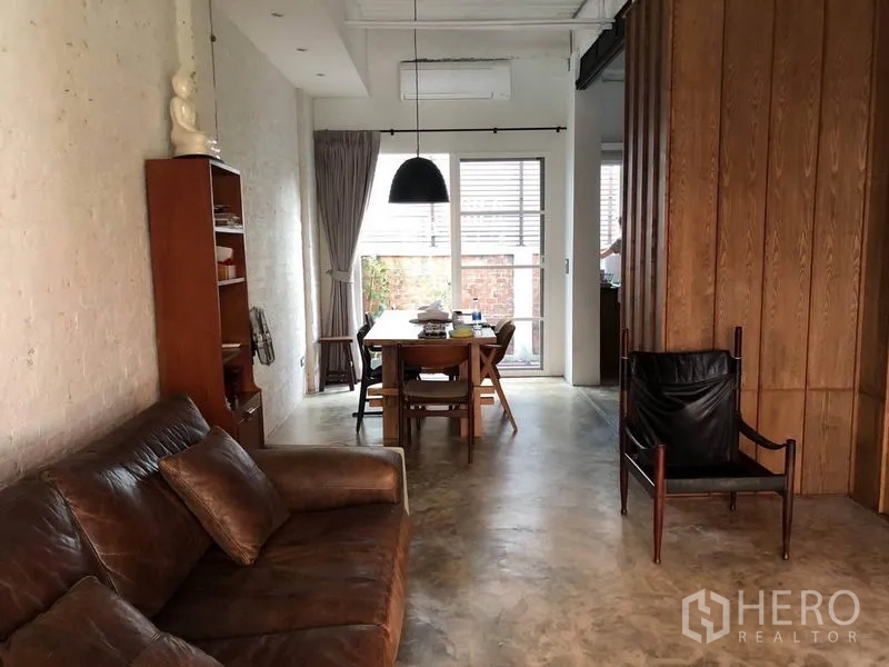 联排别墅 出售在Wang Thonglang, Bangkok - 客餐一体空间，皮沙发、吊灯，并有玻璃门通向小庭院。