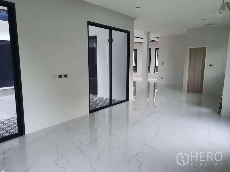 Detached House for rent in Phra Khanong, Bangkok - Open-plan area with glossy marble floors and a black-framed sliding glass door.