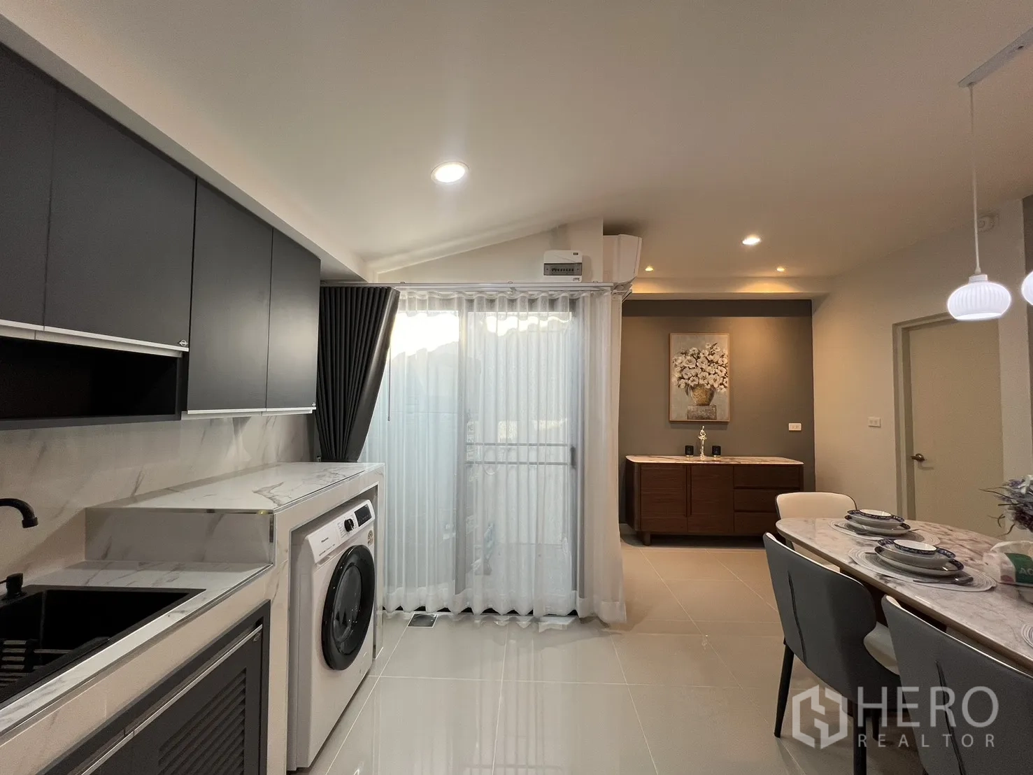 联排别墅 for rent in Bang Phli, Samut Prakan - 现代厨房带洗衣机、黑色水槽与纱帘推拉门。