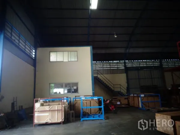 货栈 出租或出售在Lat Lum Kaeo, Pathum Thani - 高拱钢结构屋顶下的仓库内景，带两层办公室盒体与楼梯、木箱。