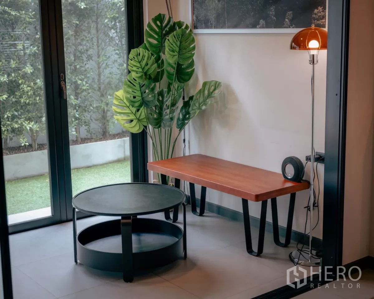 Detached House for rent or sale in Bang Phli, Samut Prakan - Corner lounge with coffee table, floor lamp and greenery beside garden doors.