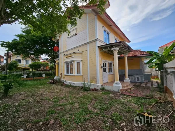 Detached House for rent or sale in Bang Lamung, Chon Buri - Rear and side yard with mature trees and a covered porch supported by pillars.